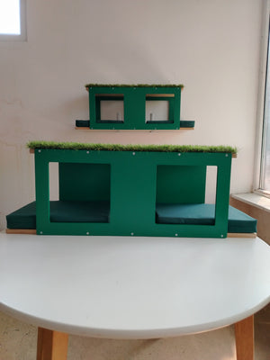 There are 2 versions of the same cat outdoor tunnel shelf. The top one is ideal for mounting on a steel mesh or onto wooden or metal beams. It has 2 large windows on both the back and front(4 in total).
The bottom shelf is ideal for mounting onto a wall. It has a full back plate and a front plate with 2 large openings.
Both have accent in emerald green and base in natural birch, with comfortable cushions in green.