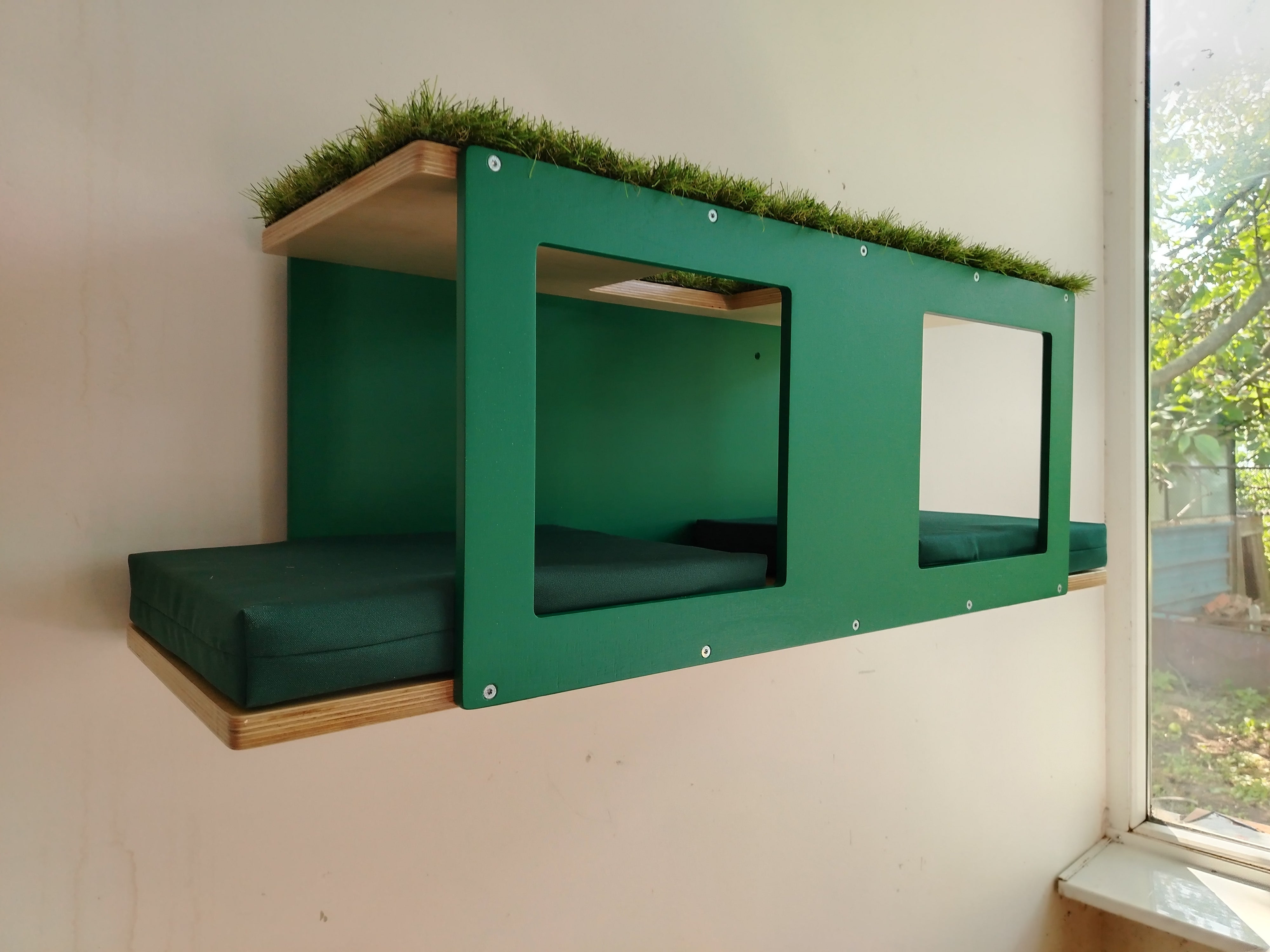 Outdoor cat enclosure shelf, wall mounted multilevel tunnel. It's with emerald green accent and birch base, with pillows in tenda green and artificial carpet on top. 